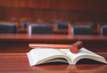 photo d'un tribunal, on voit le bureau du juge sur lequel est posé un code juridique ainsi qu'un marteau de juge
